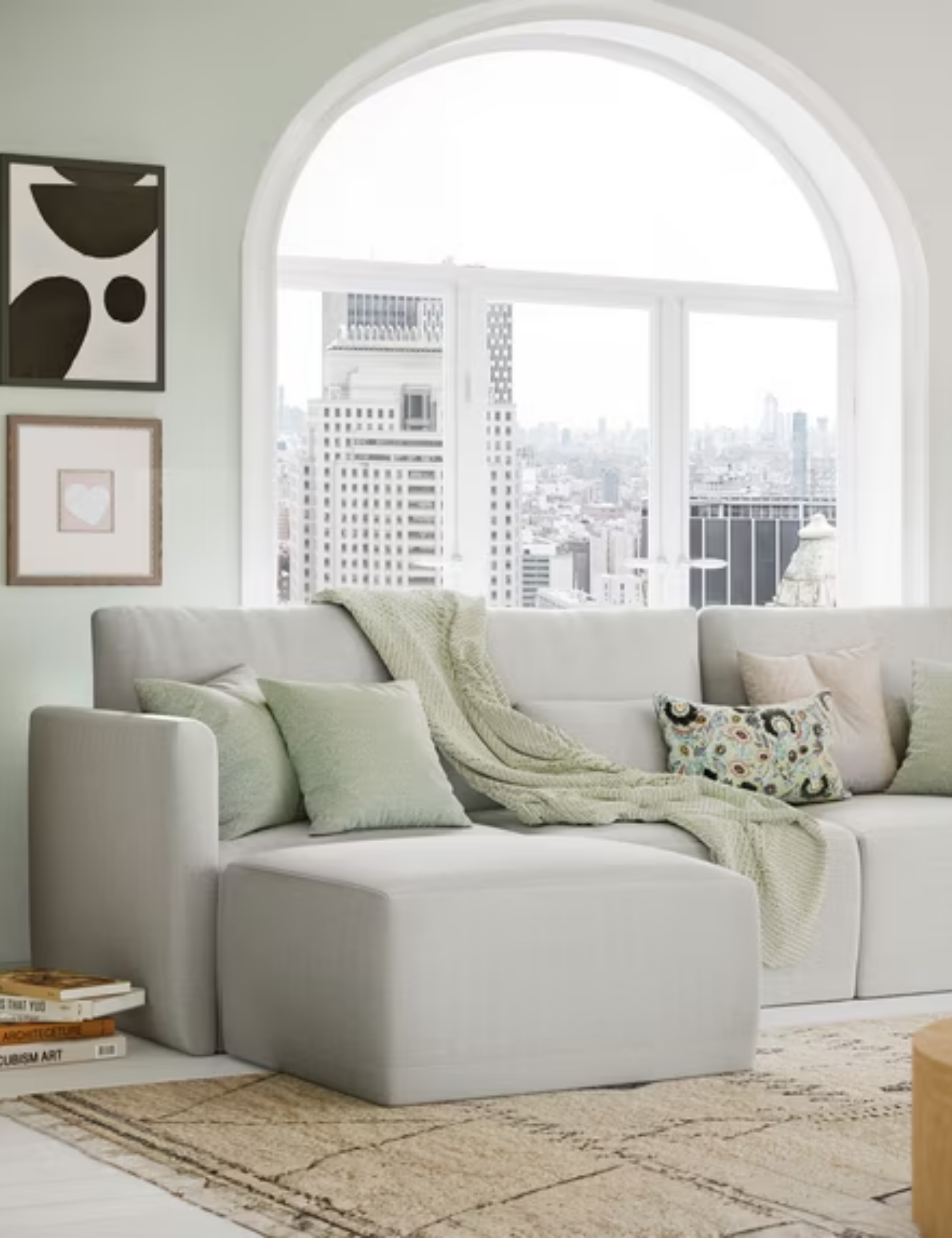 Urban living room with a large arched window, featuring a light gray sectional from Walmart's home decor line with Drew Barrymore