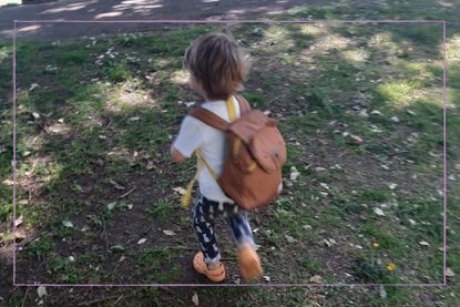 Child with backpack on running through park