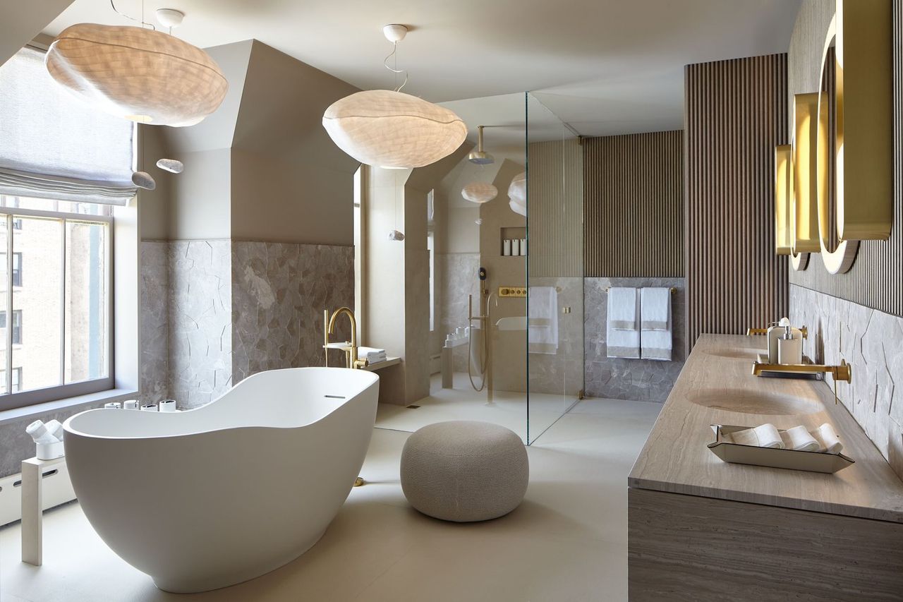 A bathroom decorated with minimalist, warm modern furnishings including paper lanterns, textured walls, and simply shaped bathtubs and accessories lets plenty of natural light in.