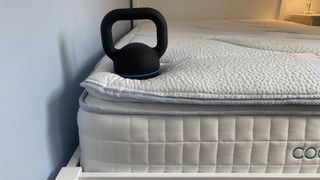 A weight rests on the corner of the Sleepeezee Cool Rest 1800 Mattress, demonstrating edge support