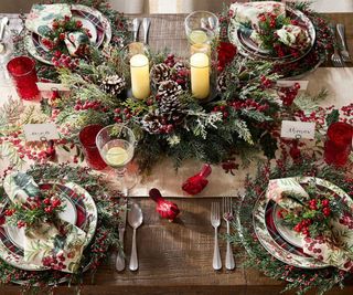 A Christmas table filled with greenery, berries, and candles