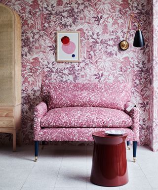 pink living area with patterned wallpaper and sofa