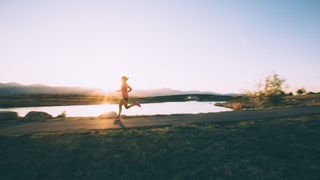 Woman running in shorts and top in early morning sunlight