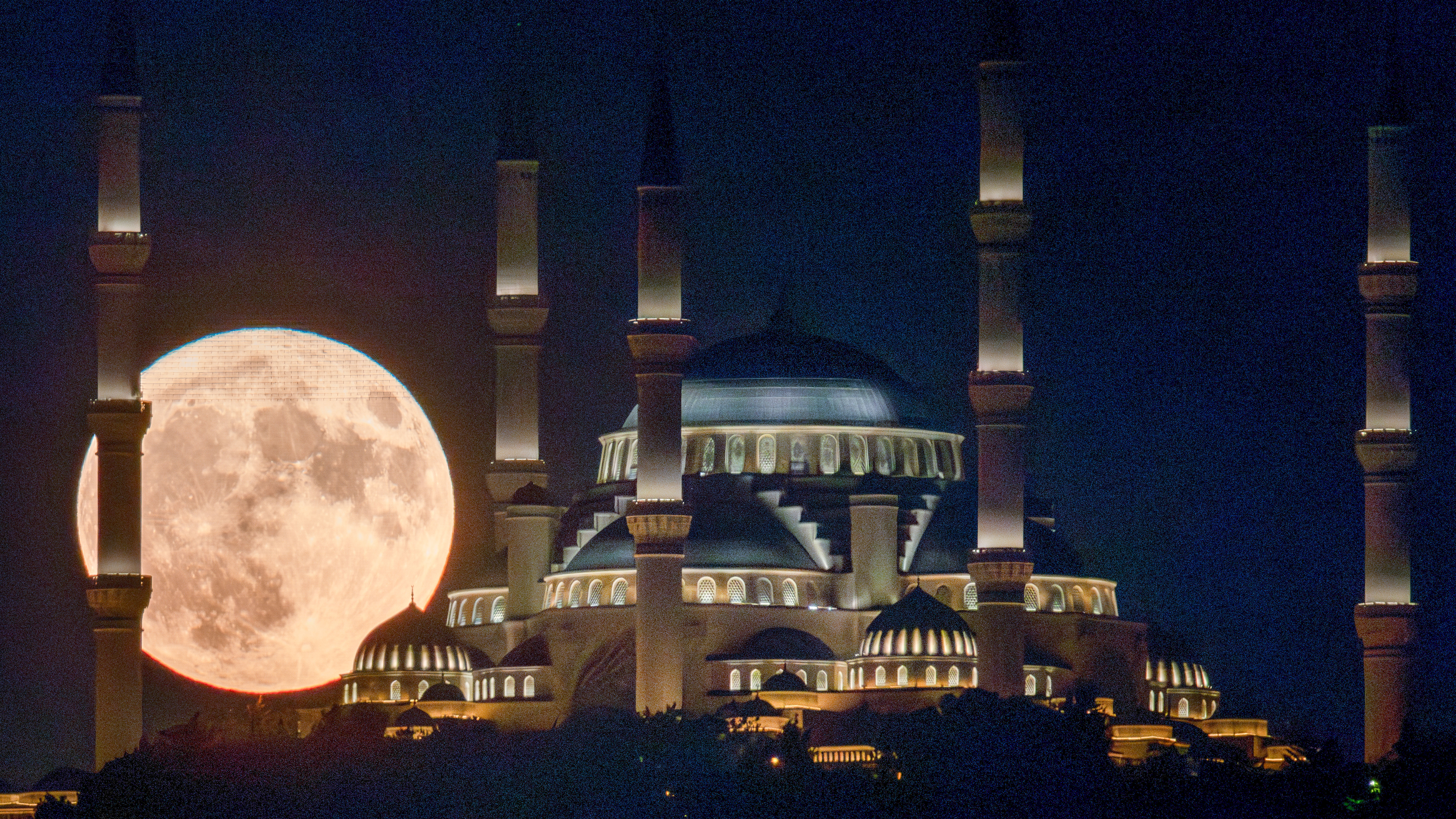 The Sturgeon full moon rises behind Istanbul's Camlica Mosque on August 01, 2023 in Istanbul,