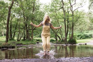 A woman jumping in a big puddle