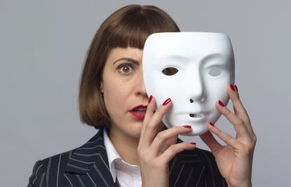 businesswoman whose face is half-covered by a white mask she's removing