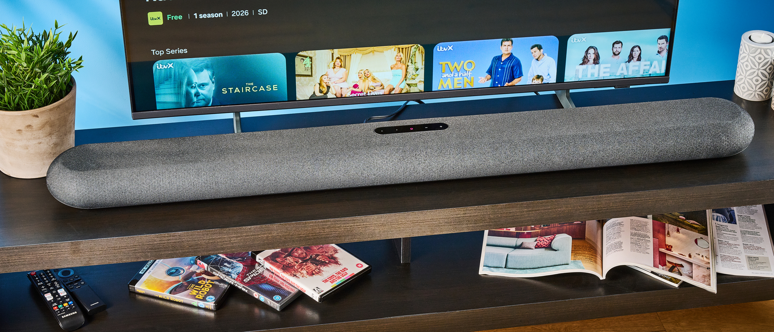 the bluesound pulse cinema soundbar photographed with a TV and the tom's guide blue background