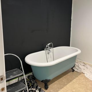 bathroom with black wall and roll top bath