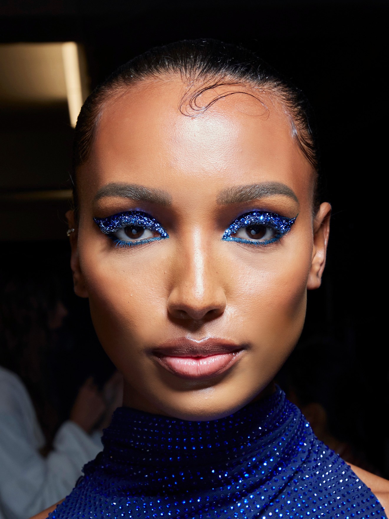 A model wearing a NYE makeup idea complete with a sapphire-toned eyeshadow and sparkles.