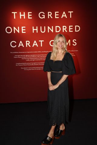 sienna miller at a london event wearing a black matching set and clogs.