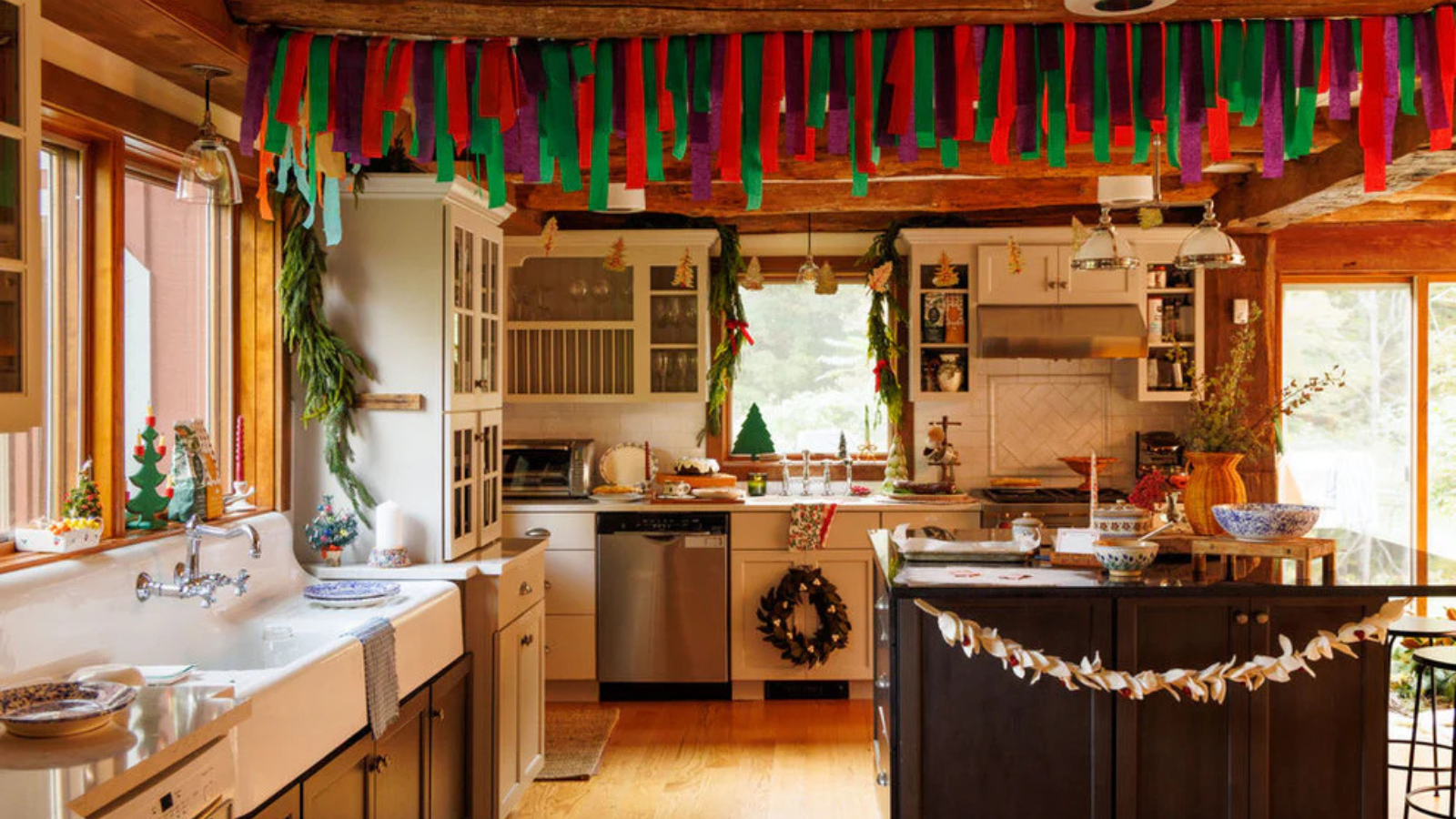 a kitchen decorated for Christmas with various handmade trimmings hanging from the ceiling, the cabinets, and Christmas decor all over the kitchen