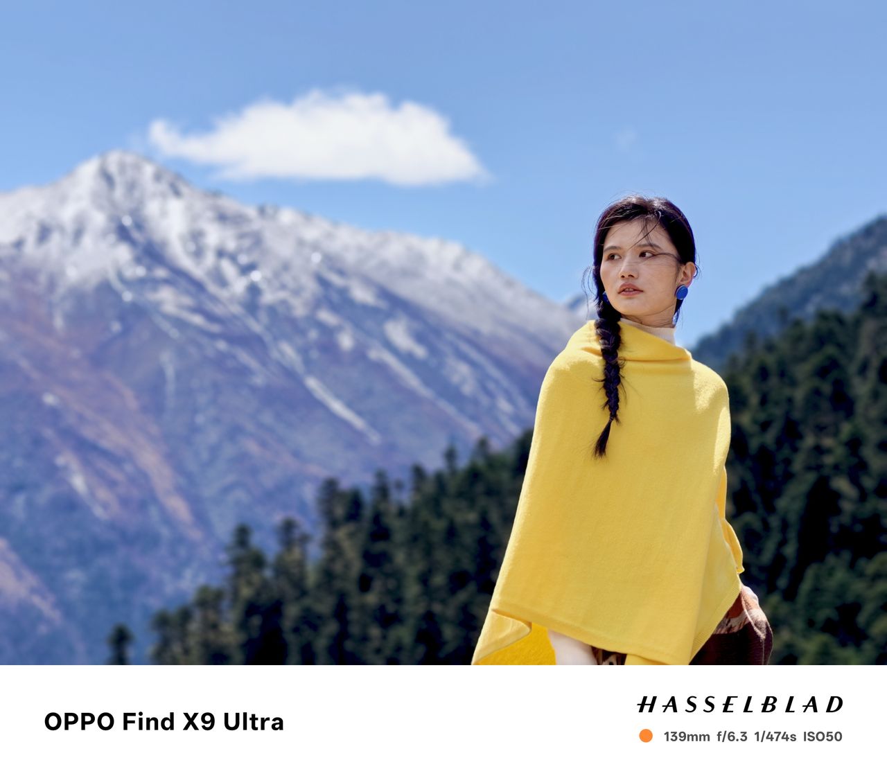 Woman in yellow shawl in front of a snowy mountain