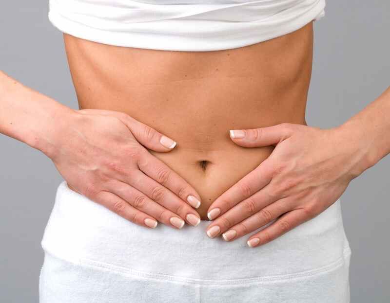 A woman places her hands over her abdomen.