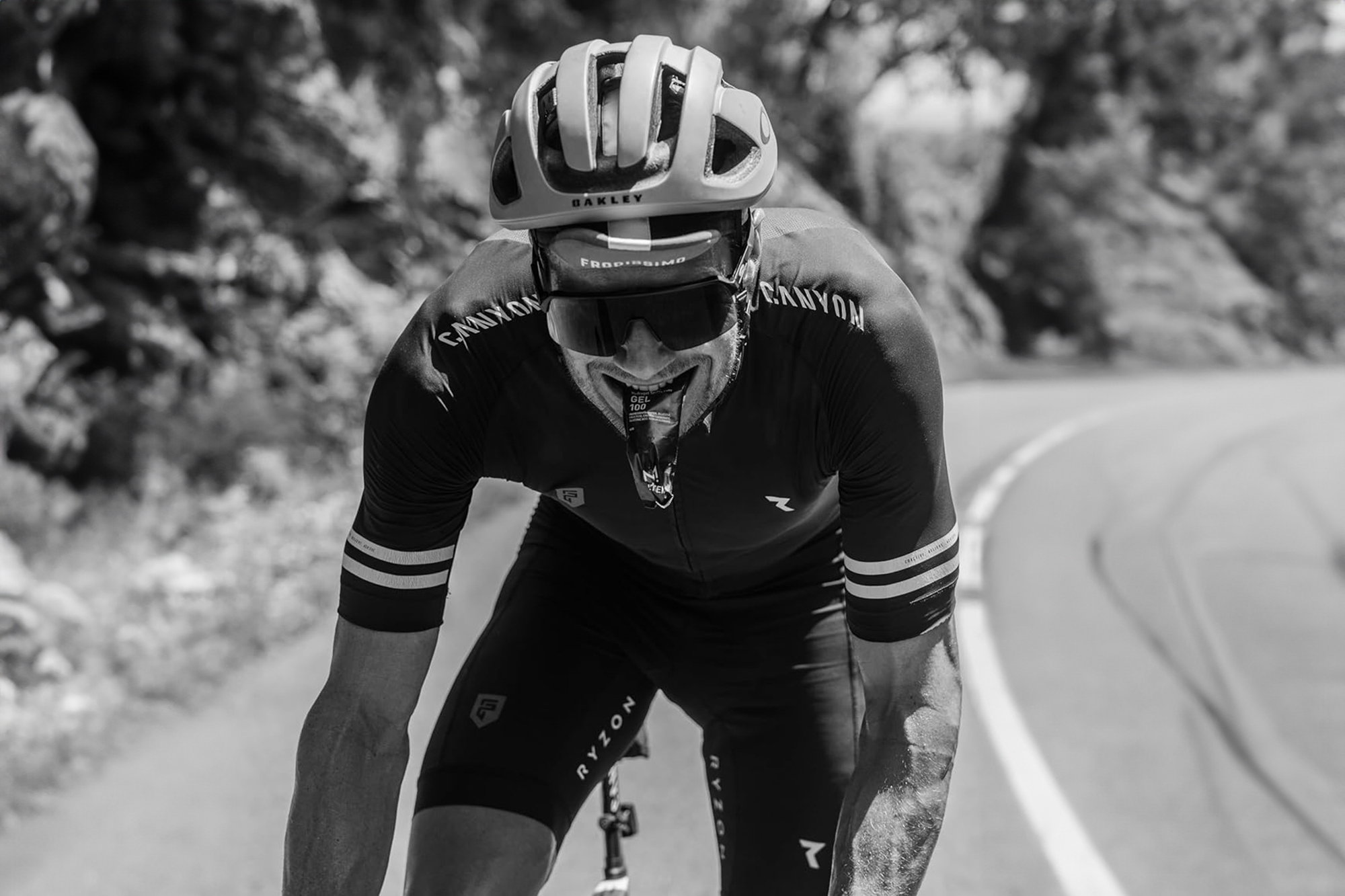 Cyclist hitting a climb hard with a Maurten gel in his mouth