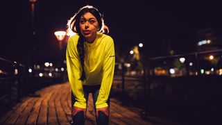 Female runner pausing for breath wearing high-vis jacket