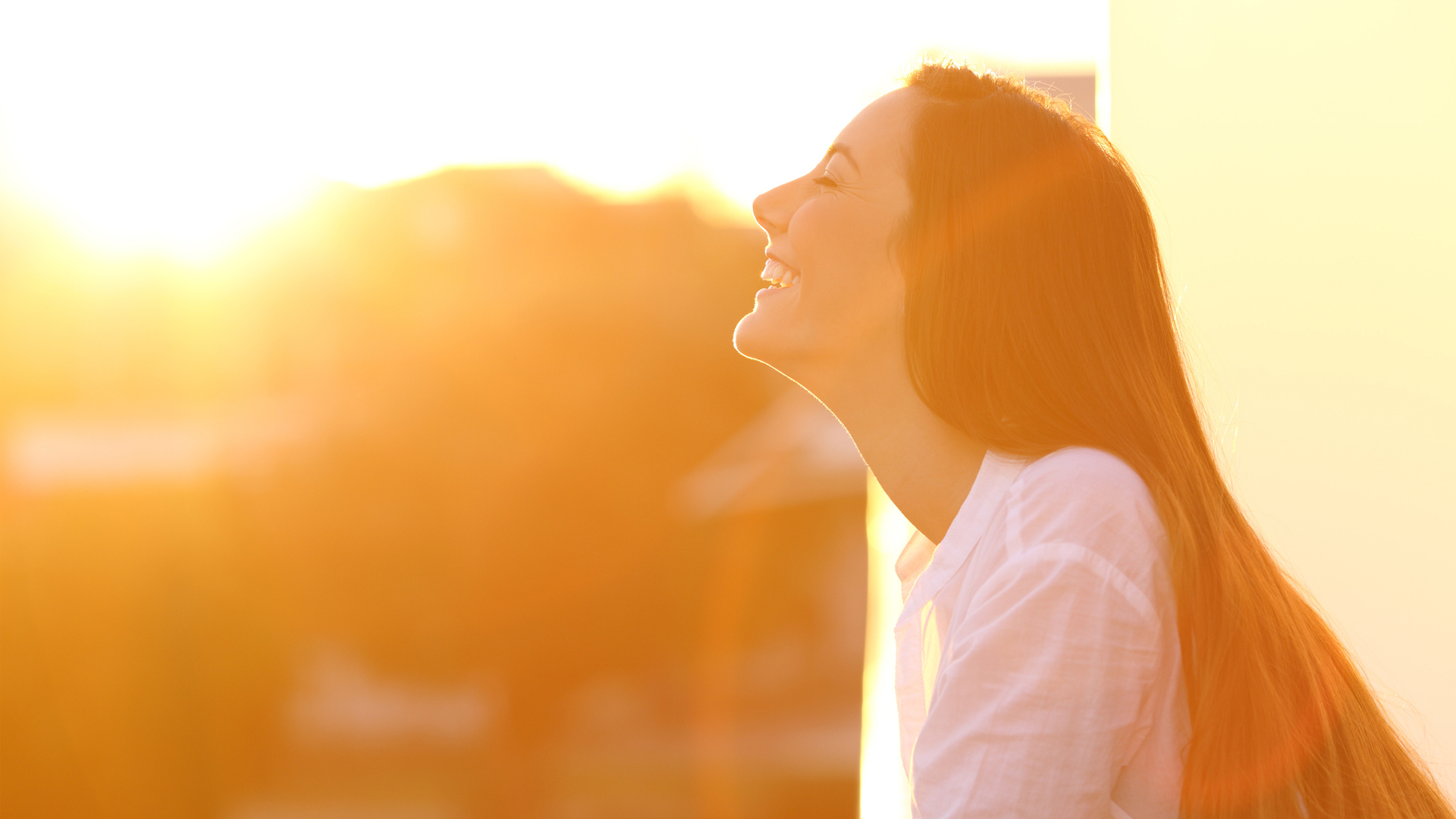 Retrato de vista lateral de una mujer feliz respirando aire fresco profundo al atardecer en un balcón de la casa