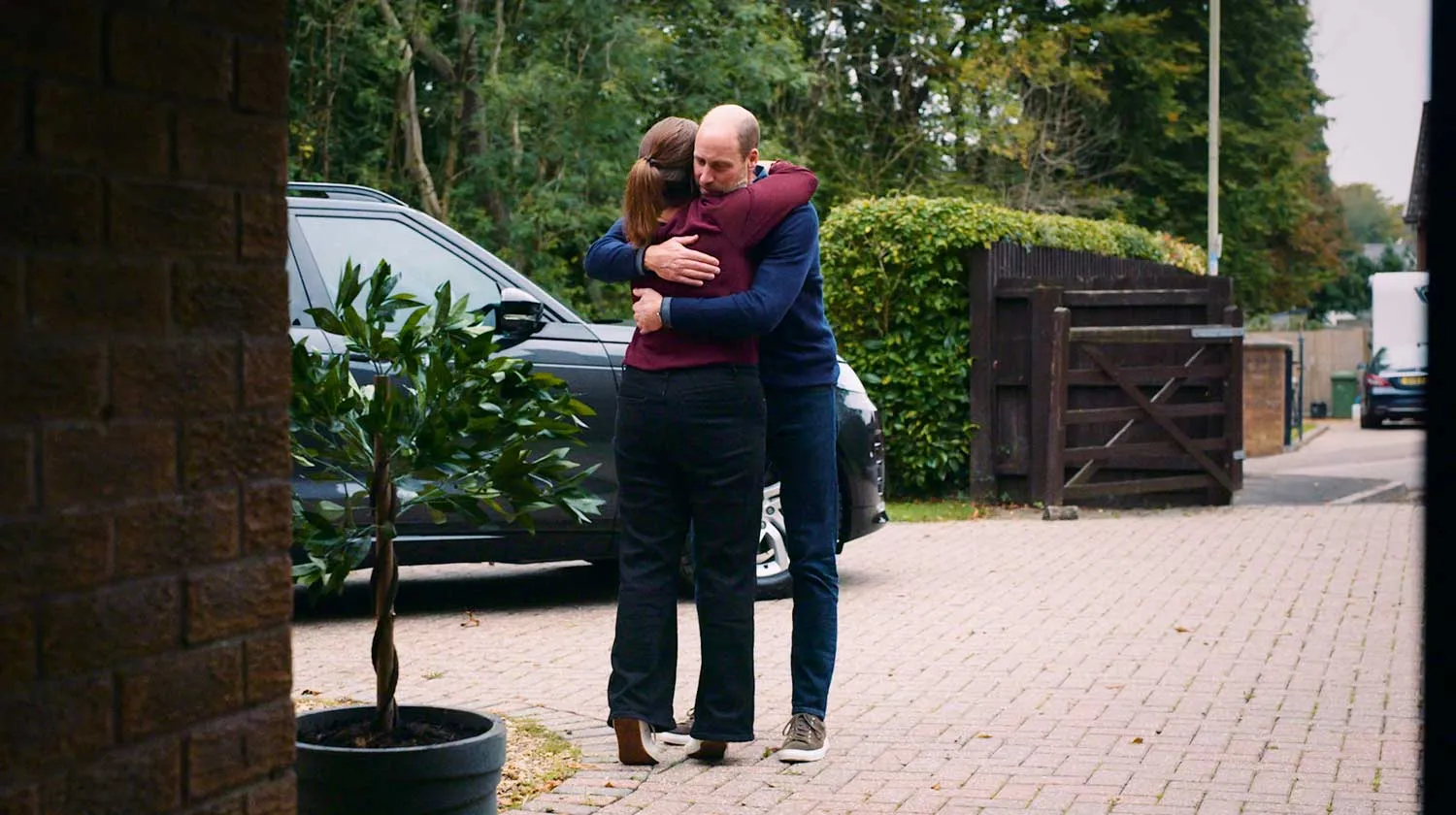 Prince William hugging a woman outside her home