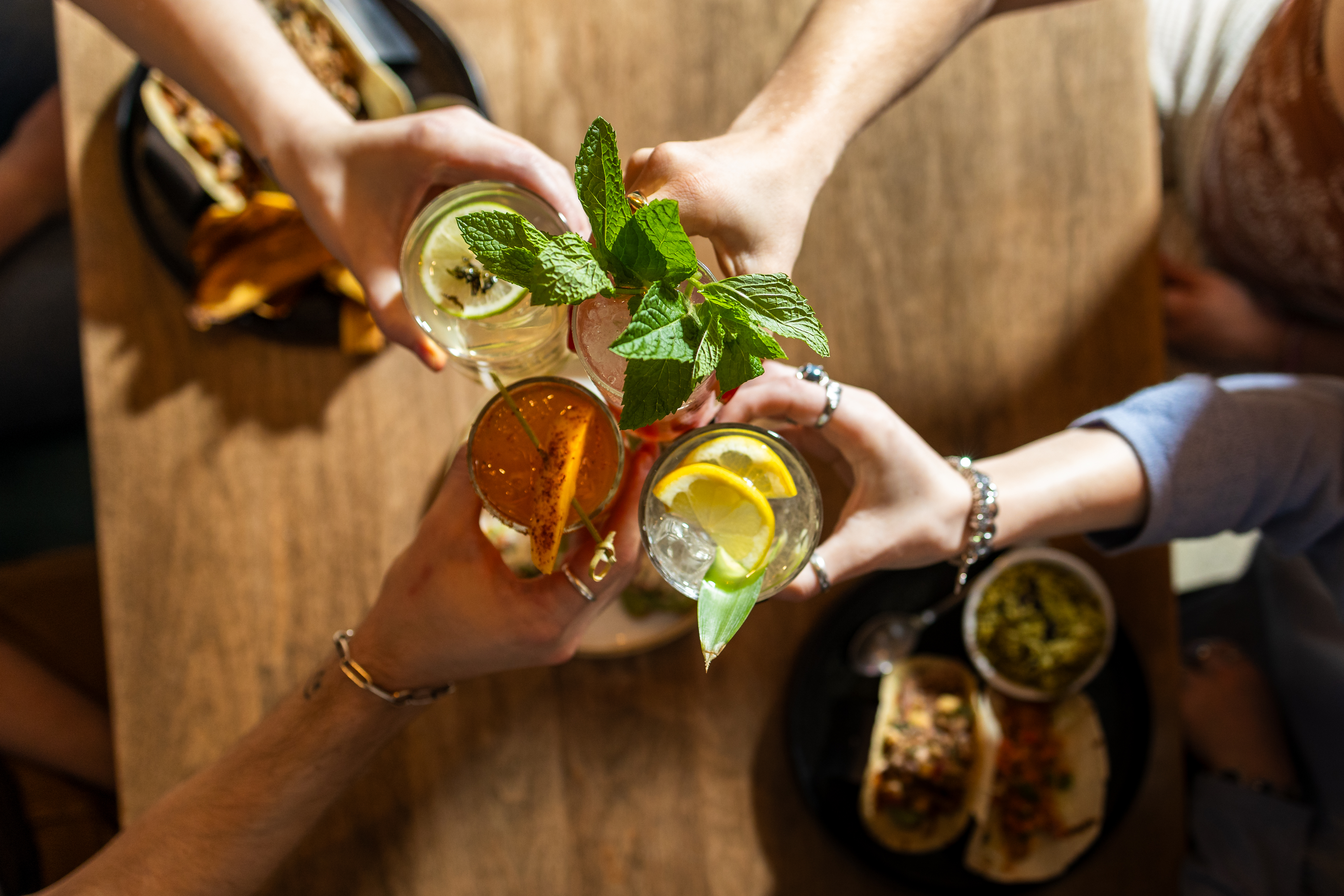 Aerial shot of four people clinking cocktail glasses together