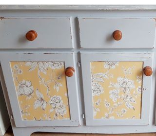 dresser with floral printed wallpaper and drawers