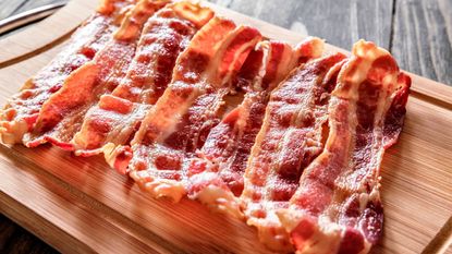 Some crispy bacon on a wooden chopping board 