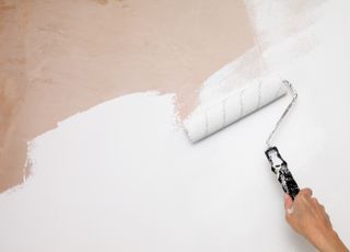 a person painting on new plaster to a wall with a roller