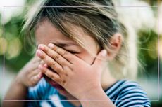 Child crying covering their eyes