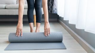 How to clean a yoga mat: image shows woman unrolling yoga mat
