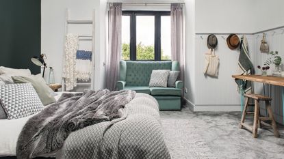 Cosy bedroom with a large bay window and window seat, double bed and feature dark blue green wall. 