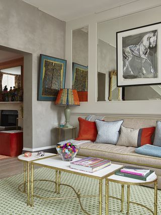 beige living room with orange cushions and lampshade