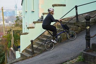 A 12-speed Brompton Electric P-Line folding bike being ridden up a steep city hill