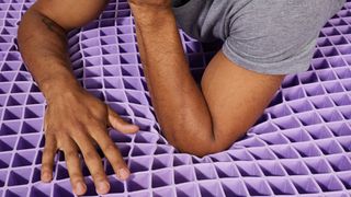 Man lying on Purple GelFlex grid to show how it compresses under pressure