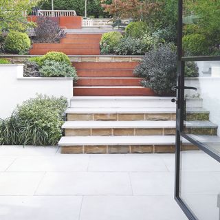 Looking out of crittal doors onto an empty patio that leads up to stone-covered steps