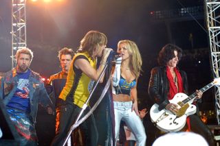 Britney Spears, Aerosmith, and *NSYNC performing during the super bowl halftime show together as britney and steven tyler lean into the mic together