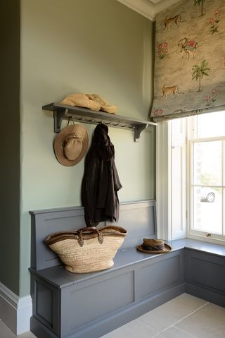 An example of mudroom ideas showing a gray wooden bench next to a window