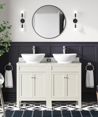 monochromatic bathroom with double sink and one large circular mirror