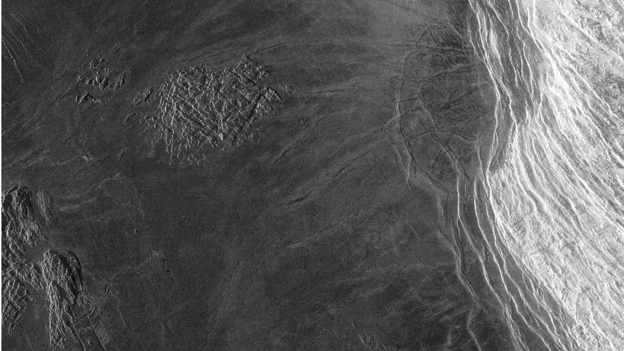 The plains of Lakshmi on Venus are made up of smooth lava flows. A tessera feature is located near the center. The abrupt edge of dark plains against it suggest that the tessera has been partially covered by lava. Additional blocks of tessera are located along the left hand edge of the image.