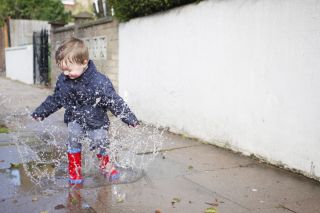 A toddler jumping in puddles