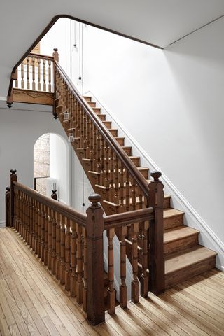 ornate wood staircase in white hallway