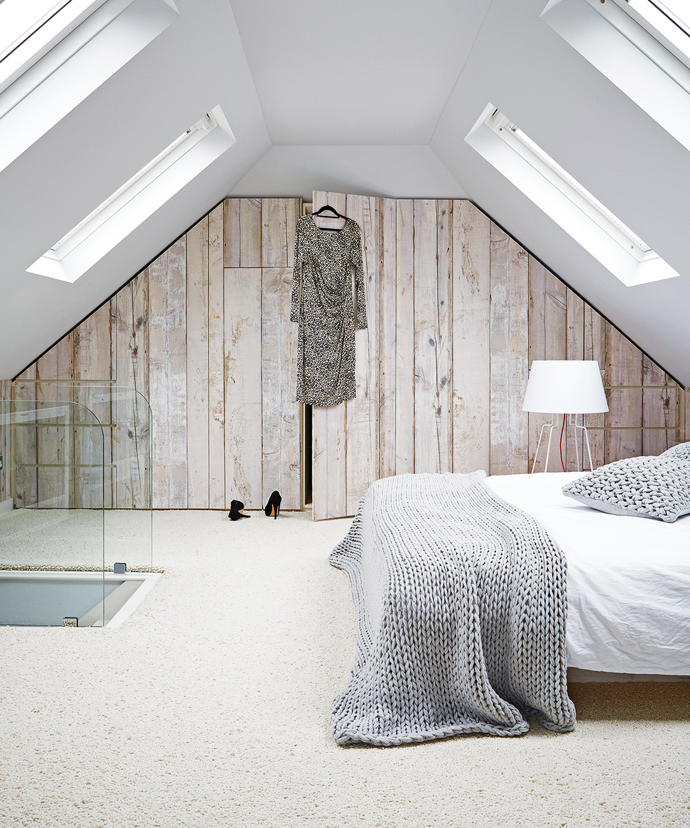 A loft bedroom with textured carpet and a wooden wall