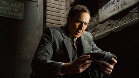 Nic Cage in Spider-Noir, holding a mask