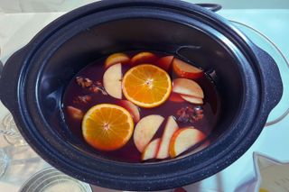 Close up of mulled wine in a slow cooker with orange slices and apple slices