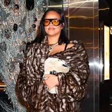 Rihanna wearing a fur coat, brown Loewe pants, and croc print heels