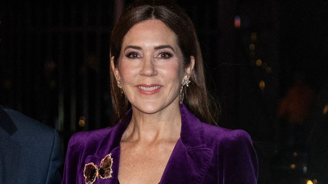 Queen Mary of Denmark, wearing a purple velvet suit, smiles as she arrives at Soelyst country house