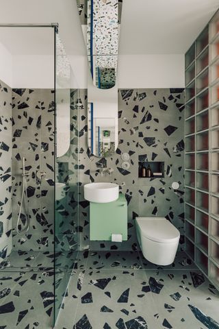 a gray terrazzo tile bathroom with a light green vanity