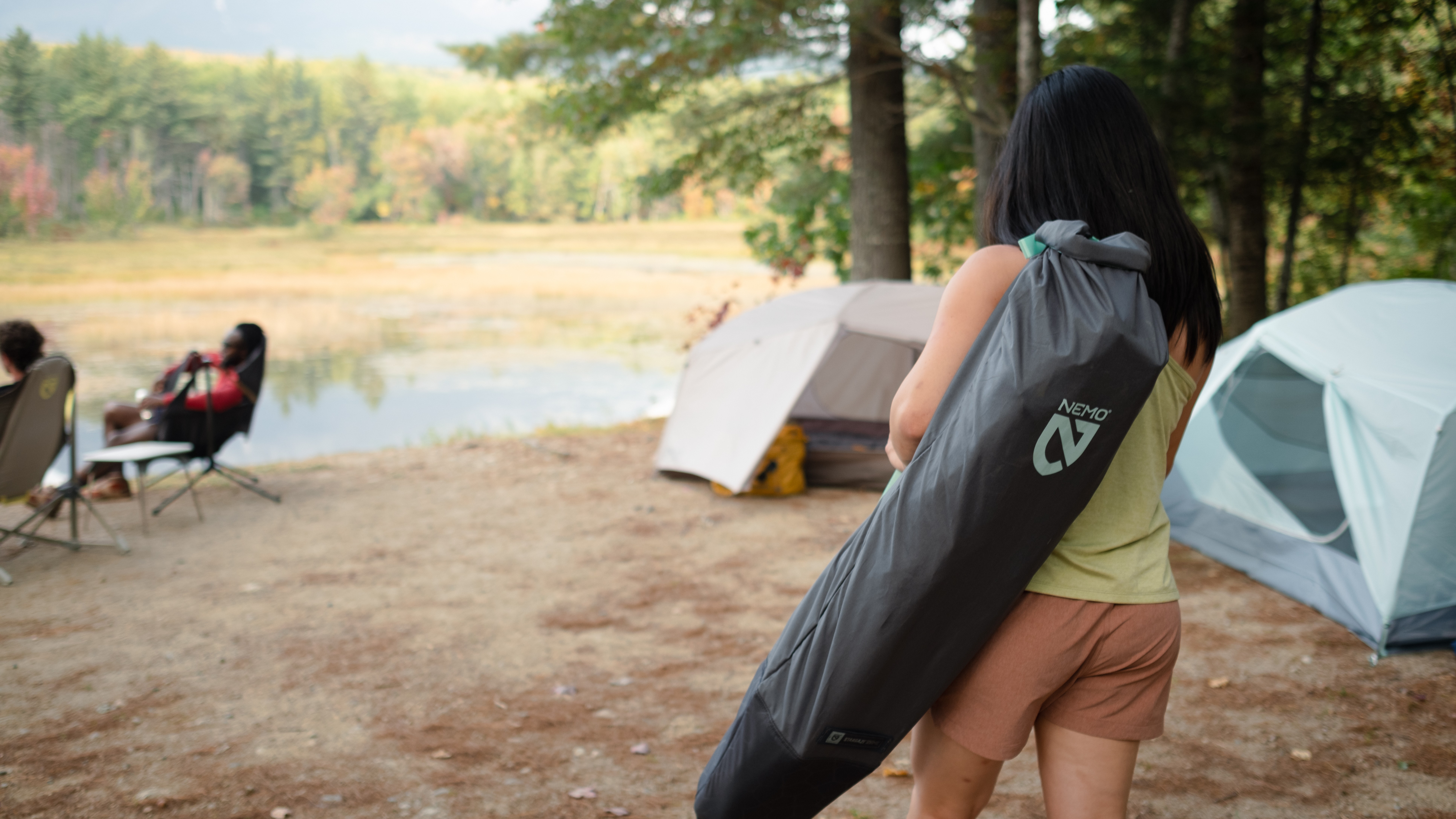 A woman carrying her Nemo Stargaze Evo X camping chair to camp