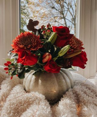 DIY white pumpkin vase idea with red flowers including roses and lillies