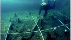 A scuba diver swimming toward a canoe underwater