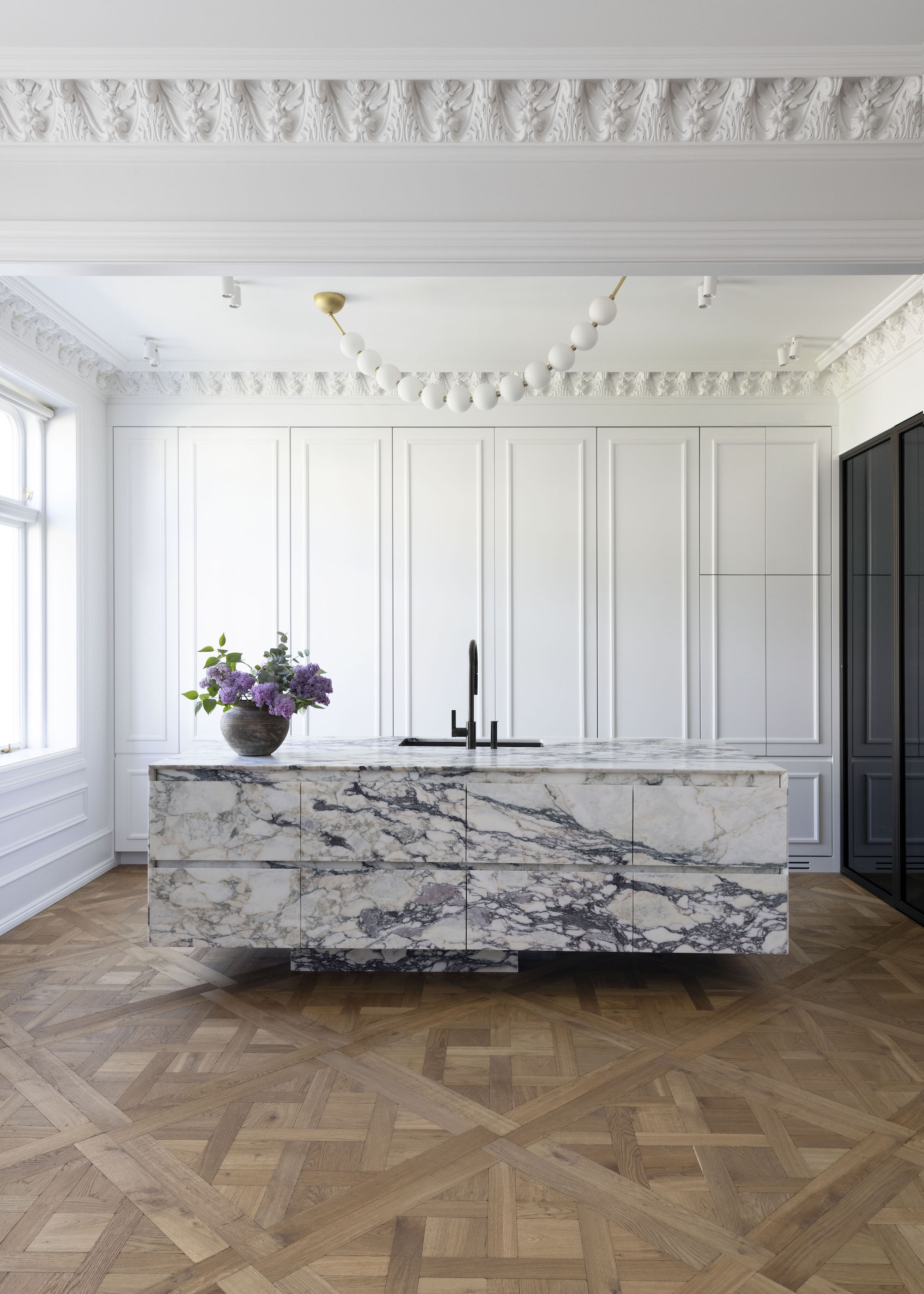Kitchen with marble island and white panelling cupboard and parquet flooring