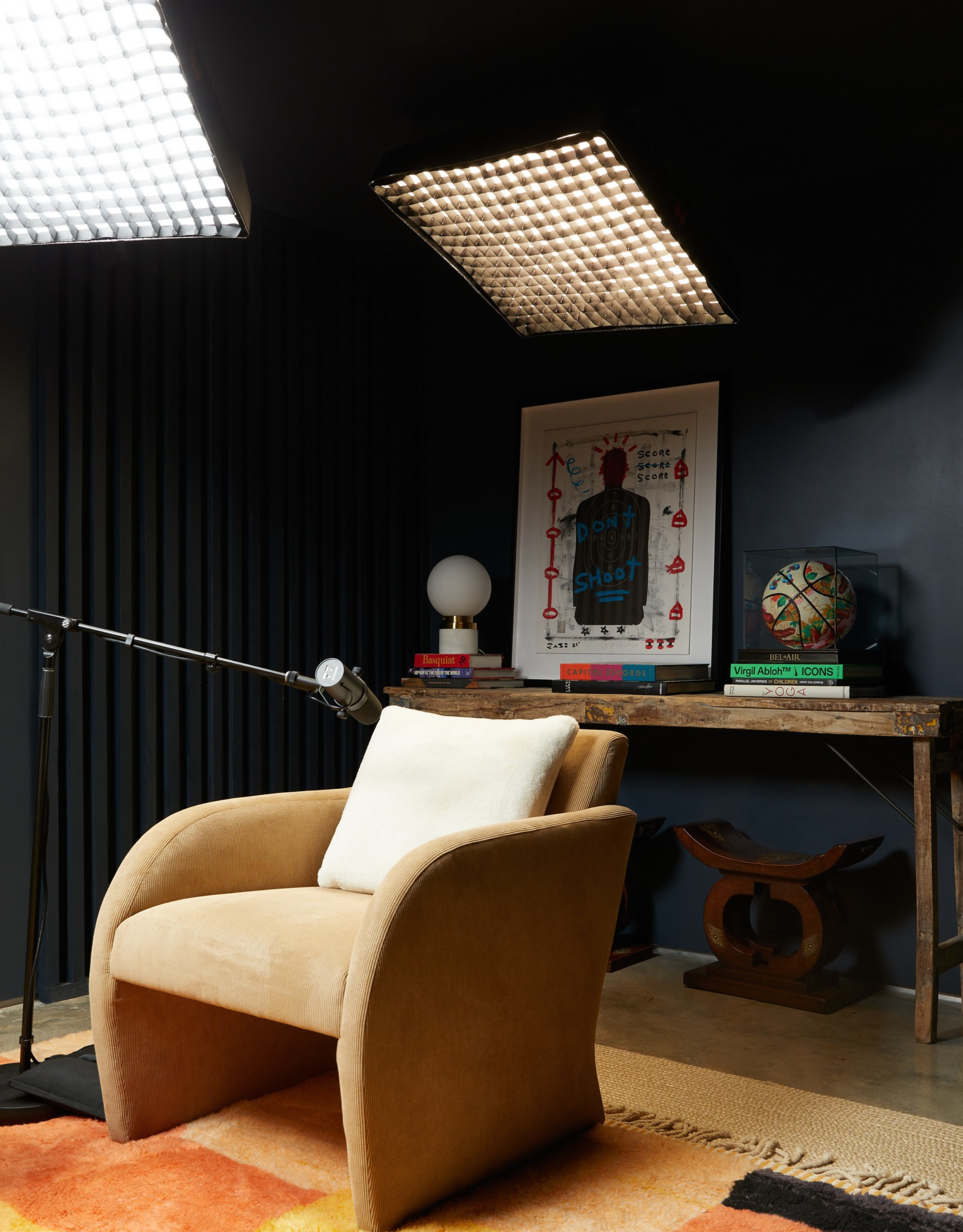 Jay Shetty's podcast studio, with dark walls, antique accessories, a beige arm chair and professional lighting