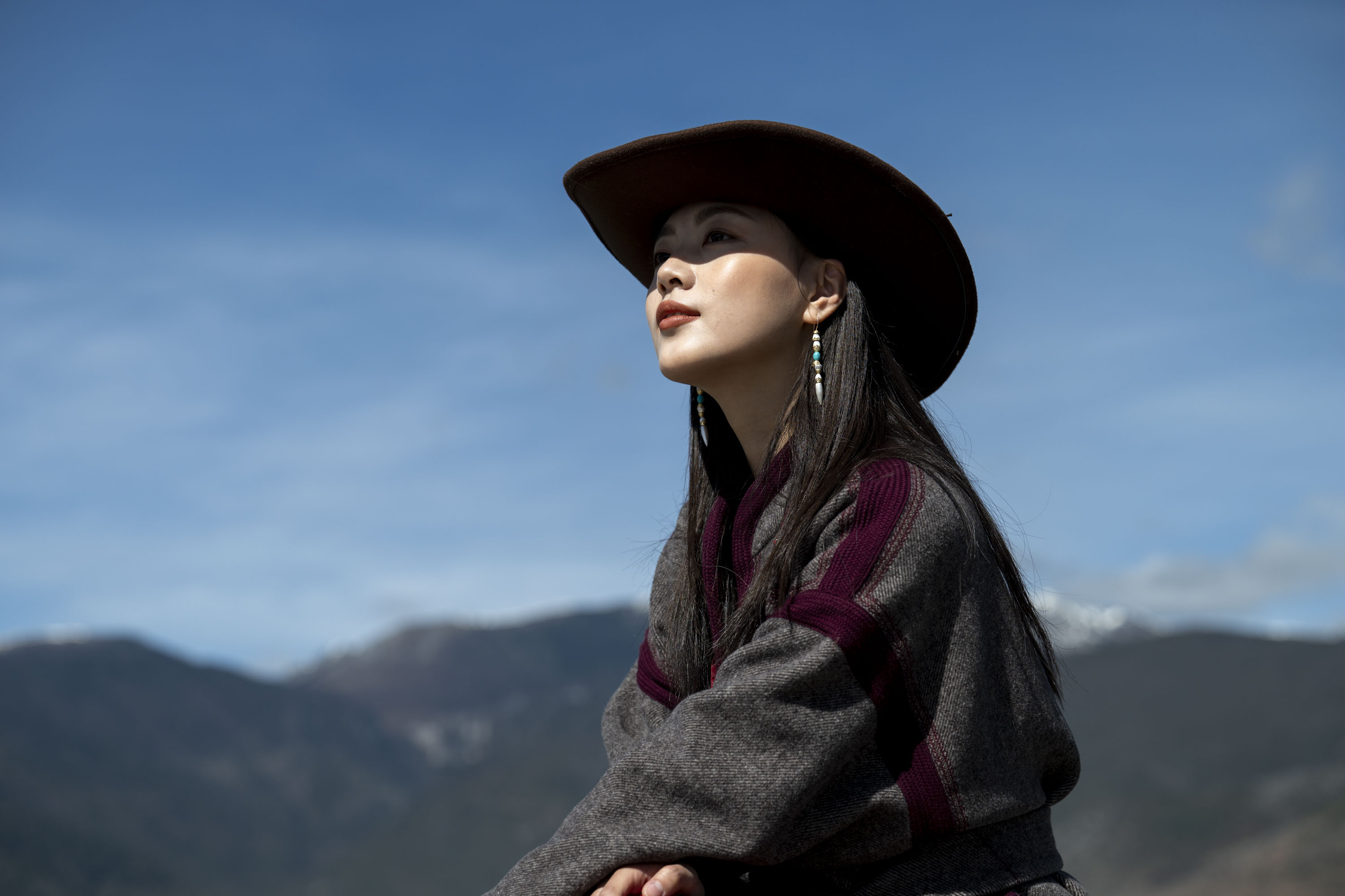 A portrait of a woman in a cowboy hat with a snowy mountain backdrop